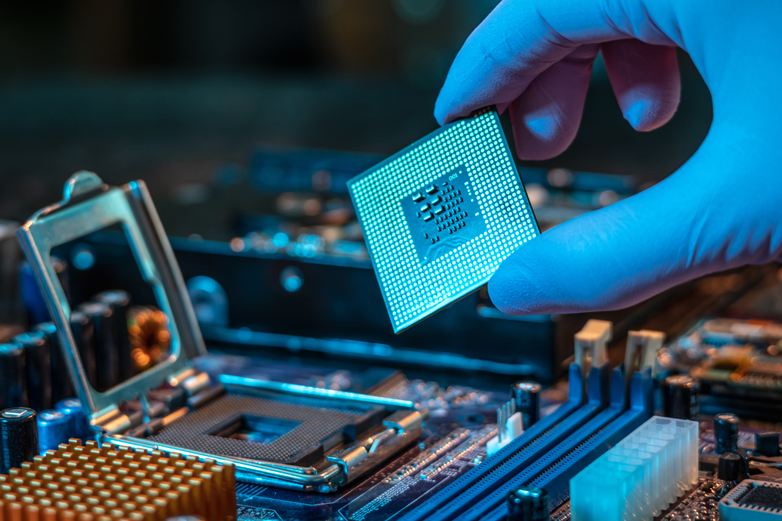 Engineer's gloved hand is holding the CPU chip on the background of the motherboard.